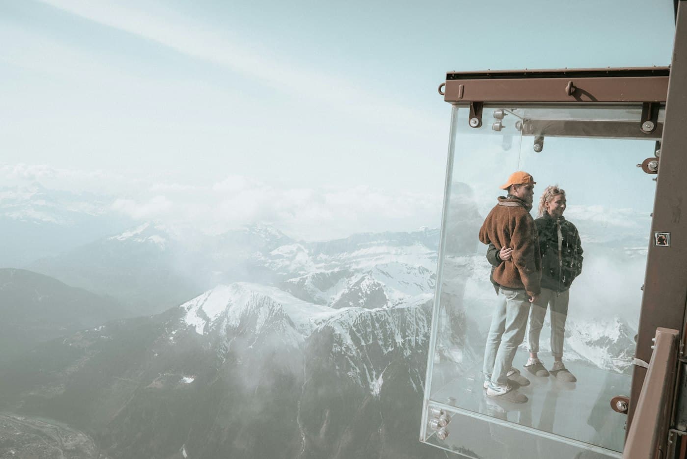 A couple standing in a glass box above the Alps at the Aiguille du Midi