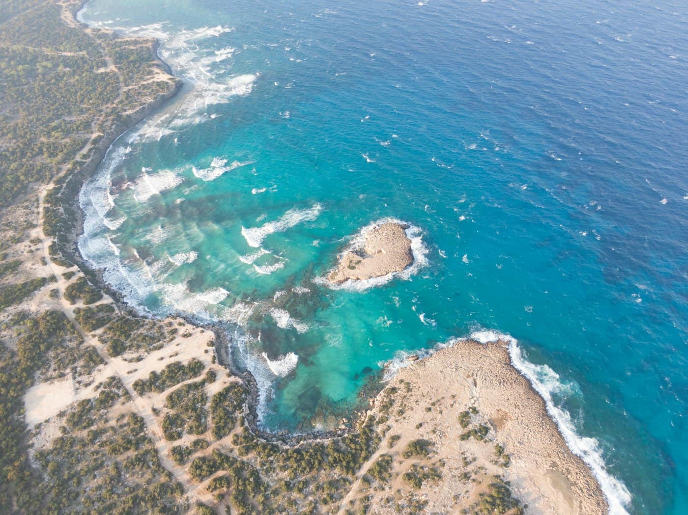 The Akamas coast from above near Neo Chorio: turquoise water, a small islet and a low rocky shore covered in scrub