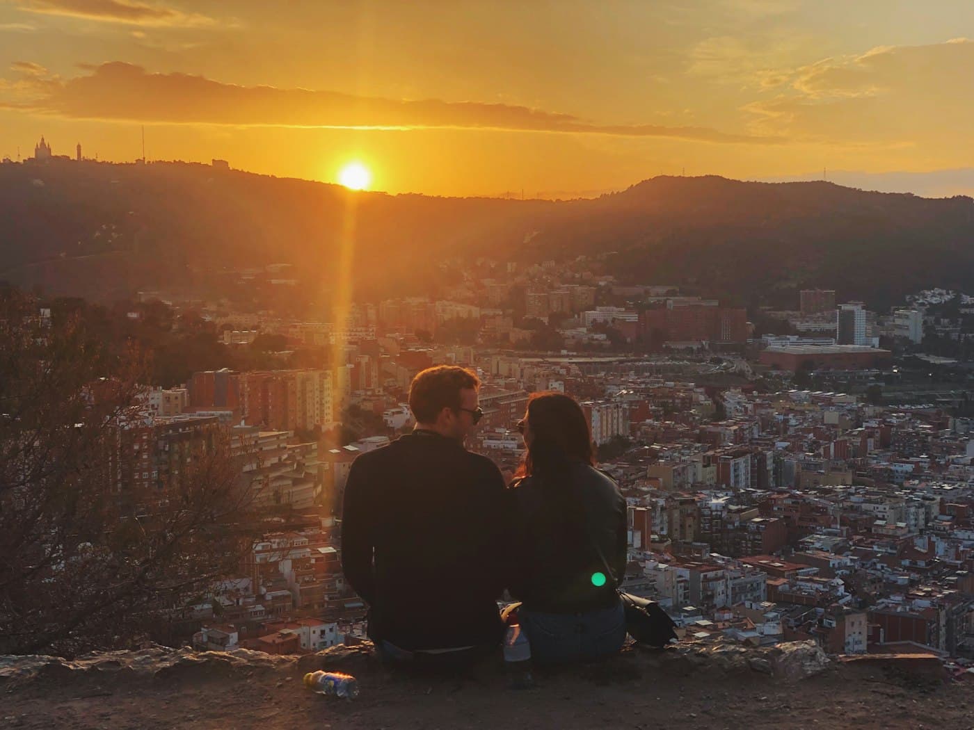 A couple on a hill watching the sun set over Barcelona