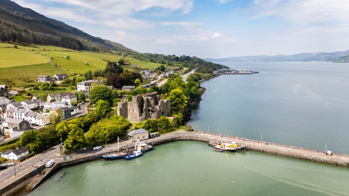 Carlingford in County Louth from the air: the ruins of King John’s Castle above the harbour and its fishing boats, the village on the green slopes of the Cooley Mountains and Carlingford Lough stretching away beyond