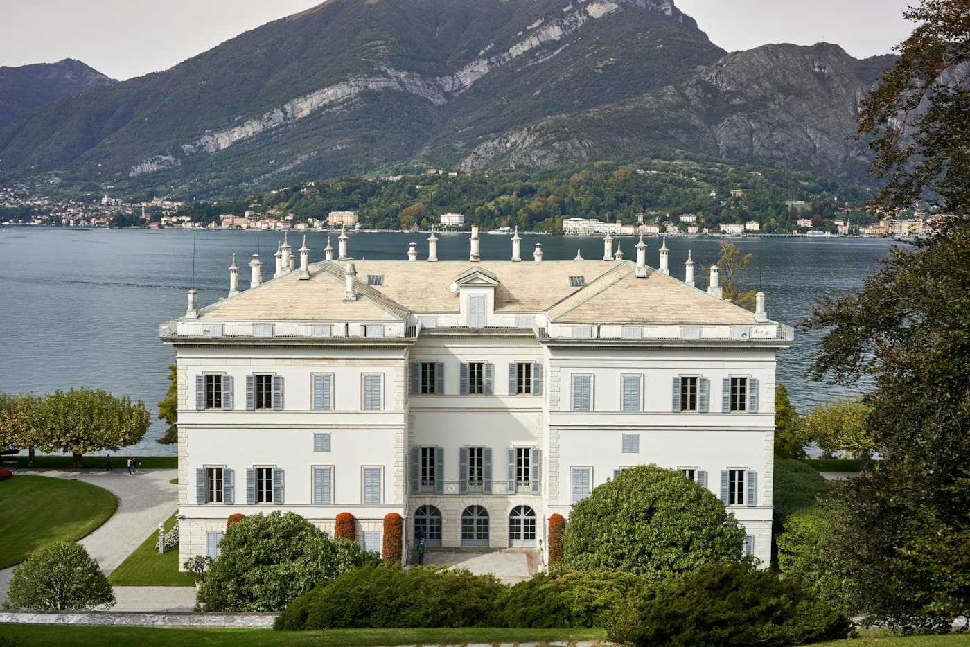 The white neoclassical Villa Melzi in its gardens in Bellagio, the lake and mountains behind