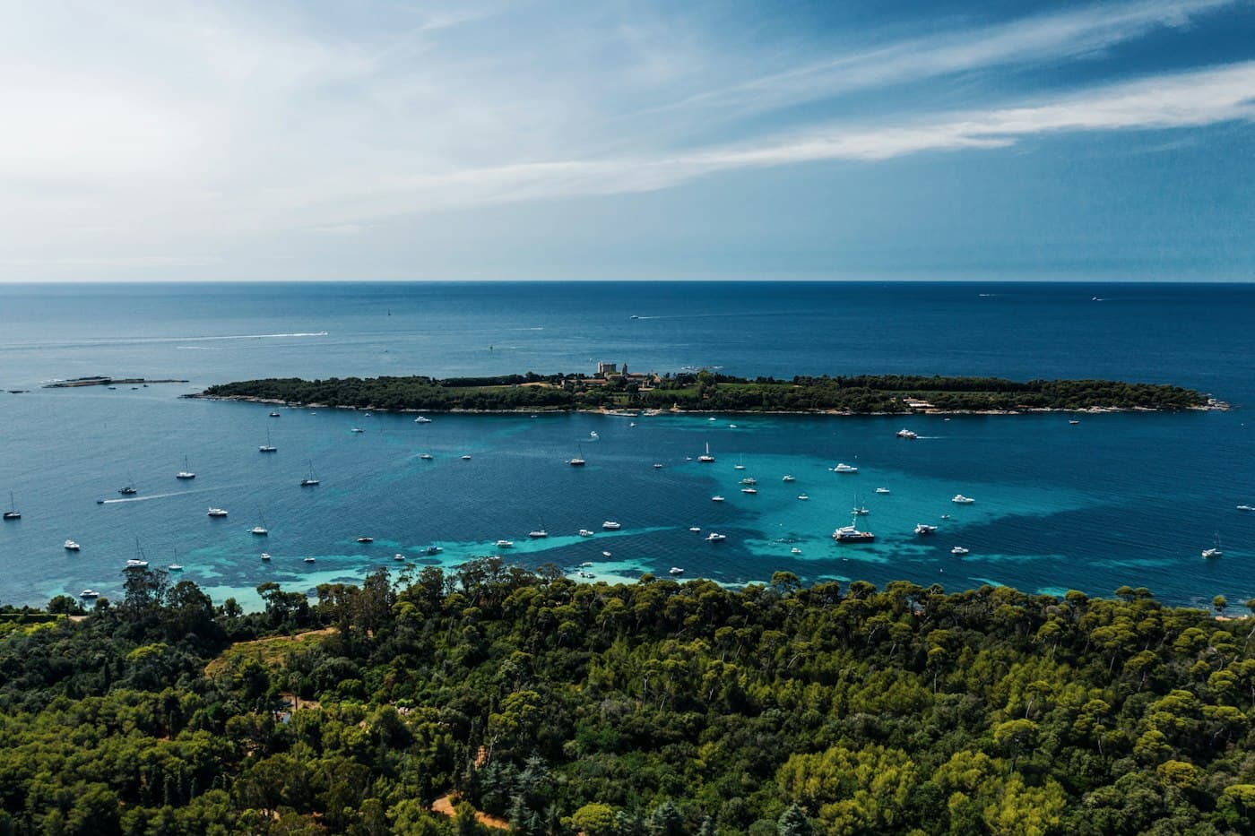 The Lérins islands from above: the pine woods of Sainte-Marguerite in front, boats anchored in the turquoise channel and Saint-Honorat with its abbey beyond