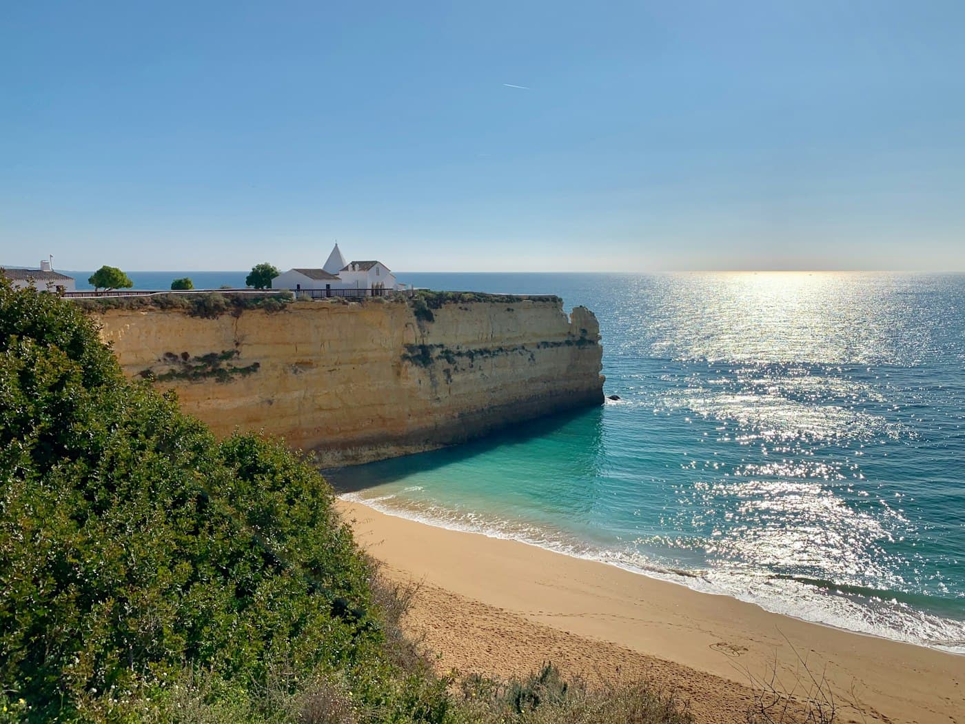 The chapel of Nossa Senhora da Rocha on its headland above the beach, the sea glittering in the sun
