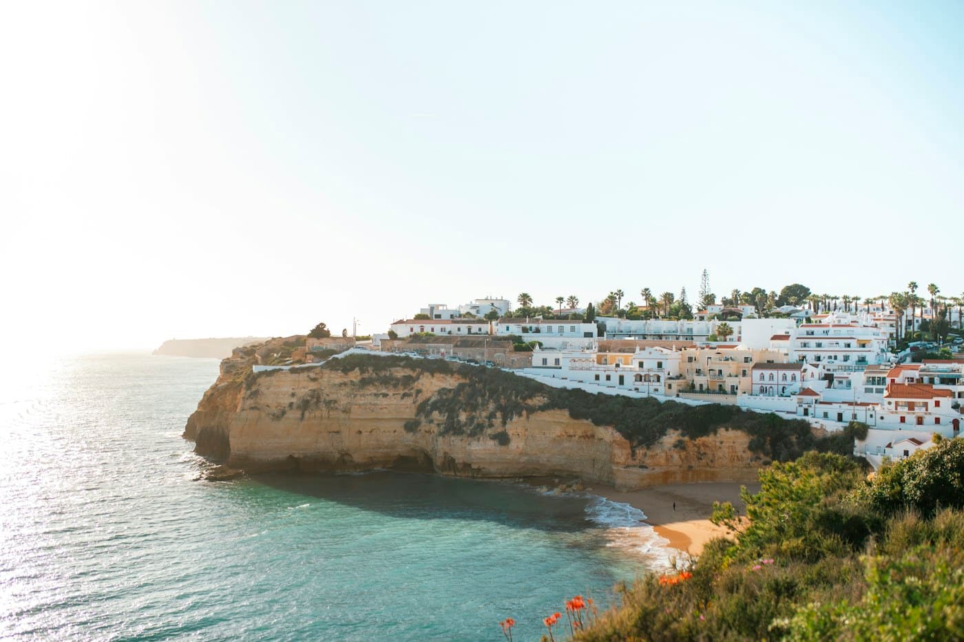 Carvoeiro’s white houses along the cliff top above its cove and small beach, the sun low over the sea