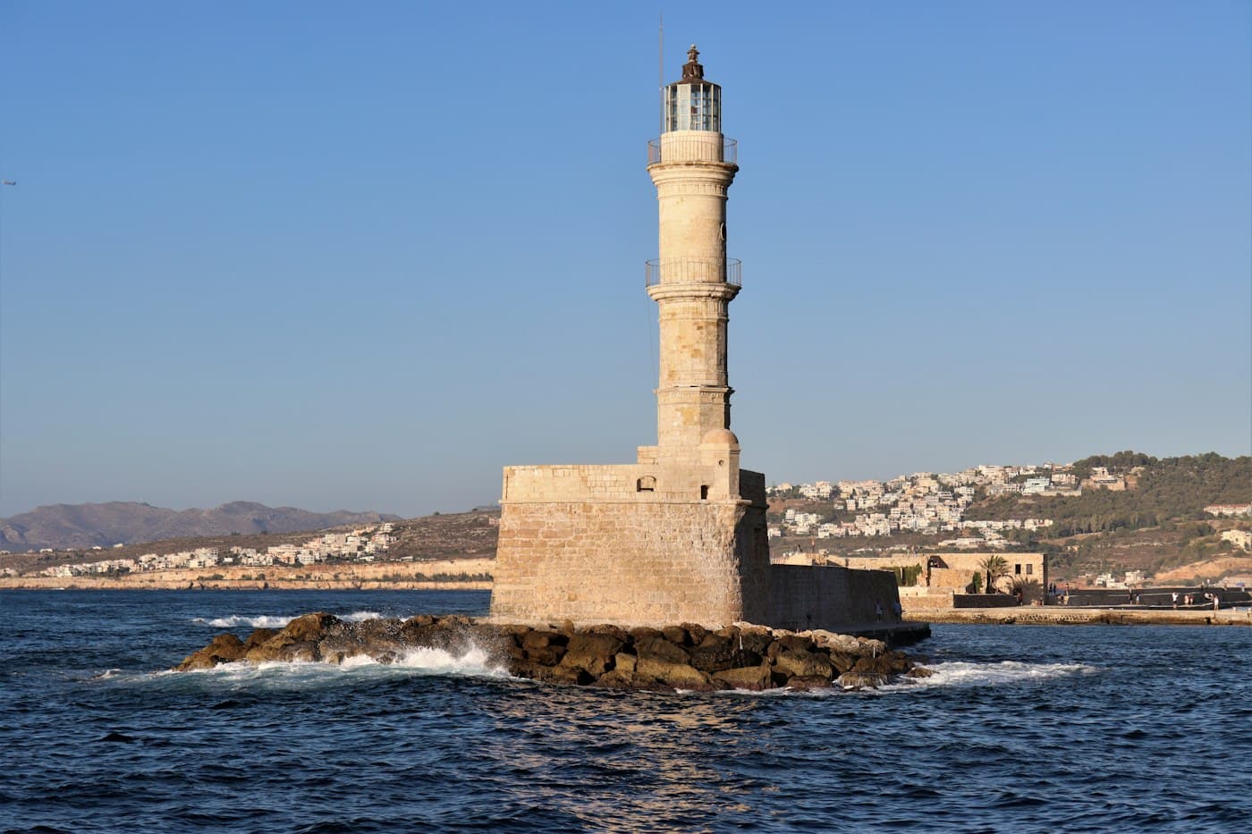 The stone lighthouse at the end of Chania’s Venetian breakwater, waves breaking on the rocks at its foot