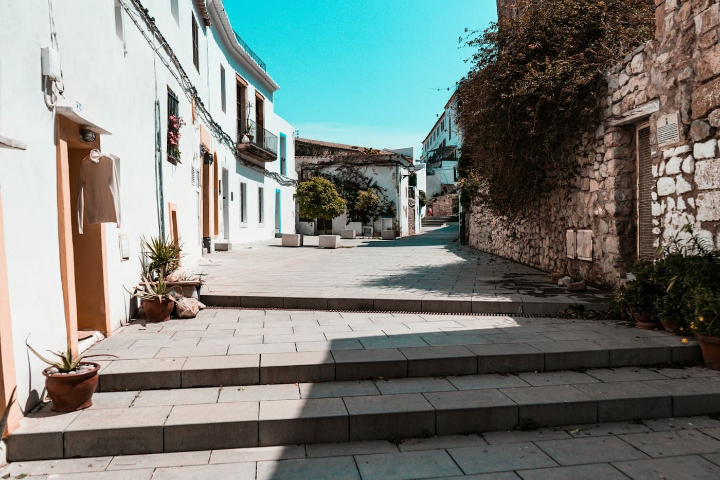Whitewashed houses, stone steps and an old wall in a quiet lane in Ibiza