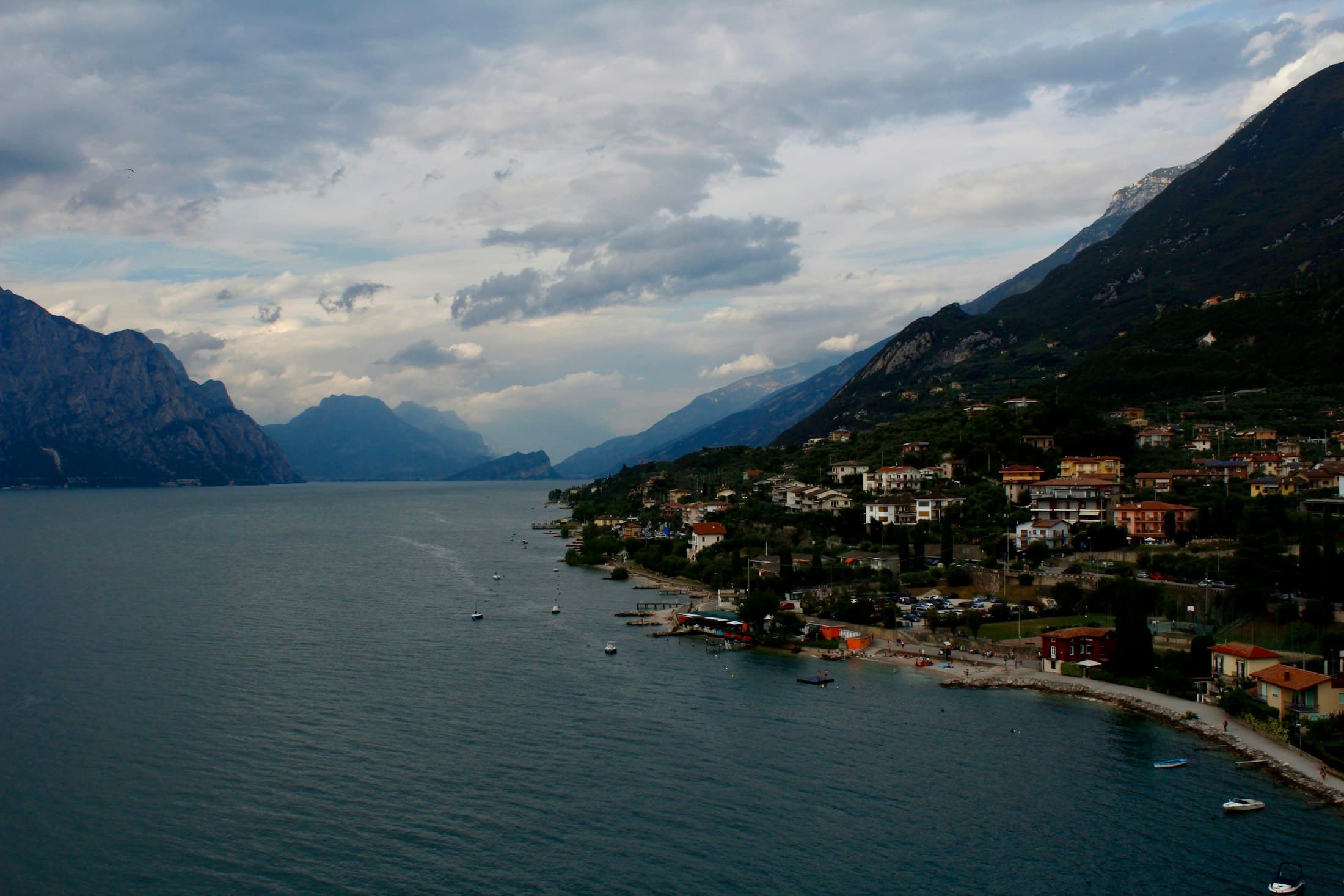 Lake Garda under grey clouds seen from above Malcesine, the shore houses at the foot of the mountains