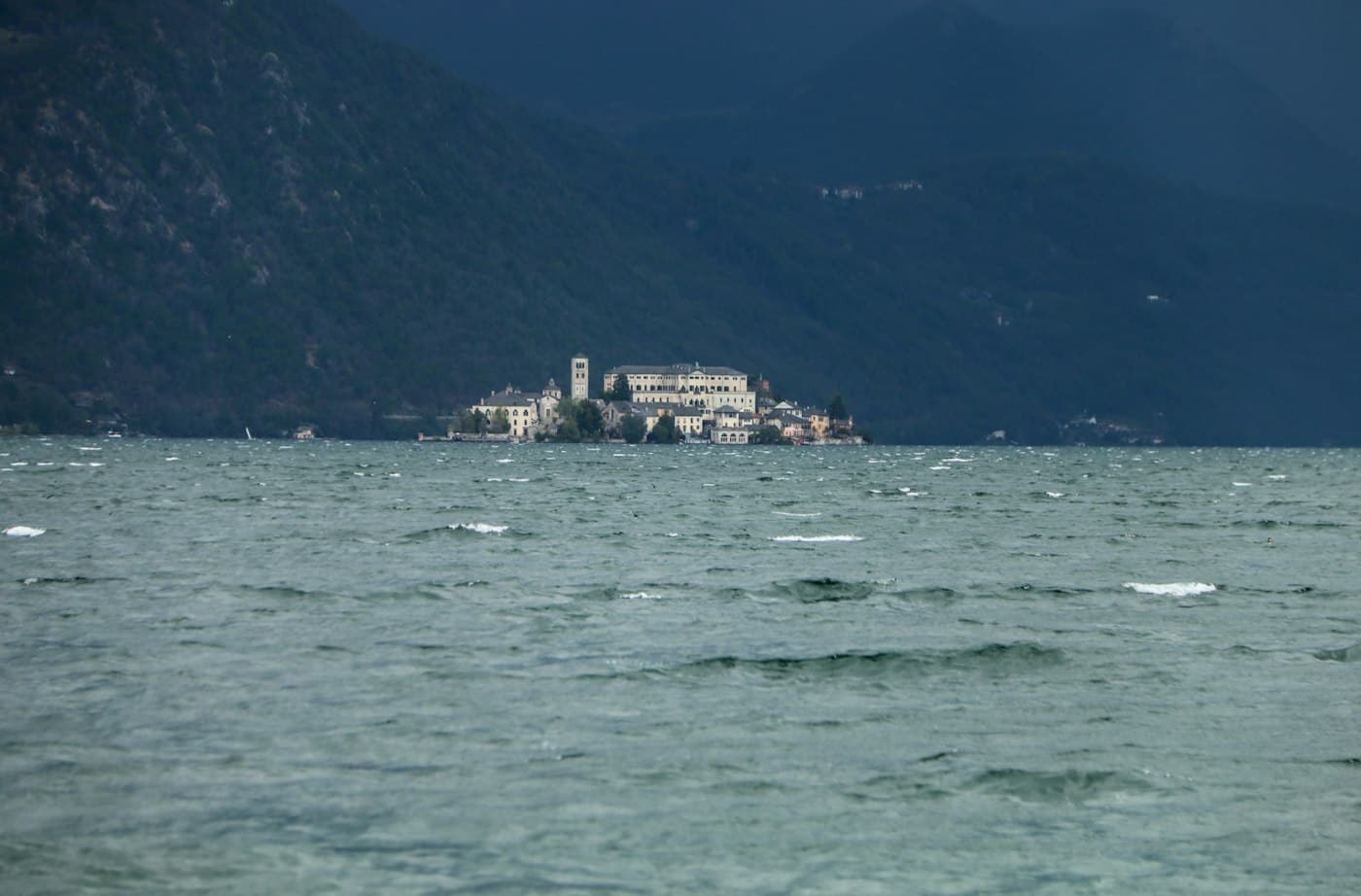 Wind-whipped water on Lake Orta and the island of San Giulio, small and pale under dark wooded mountains