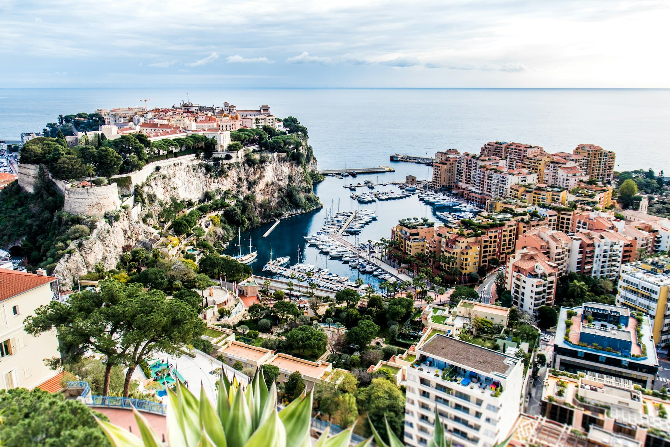 The Rock of Monaco seen from the heights above Fontvieille: the old town and its ramparts on the cliff at left, the Fontvieille marina and apartment blocks at right, the open sea behind