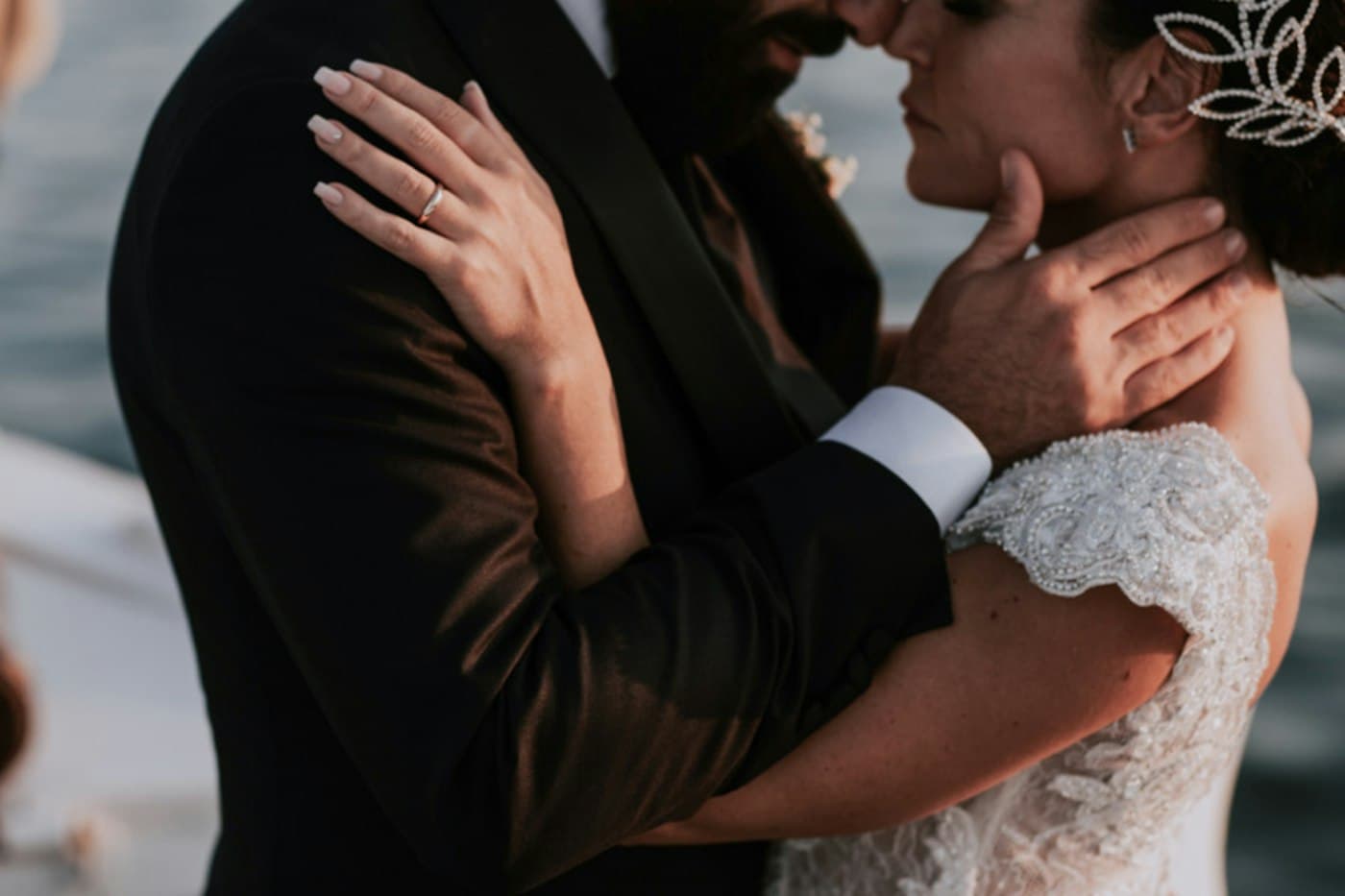 Una sposa e uno sposo stretti in un abbraccio su una barca a Positano, la mano di lei con la fede sulla spalla di lui