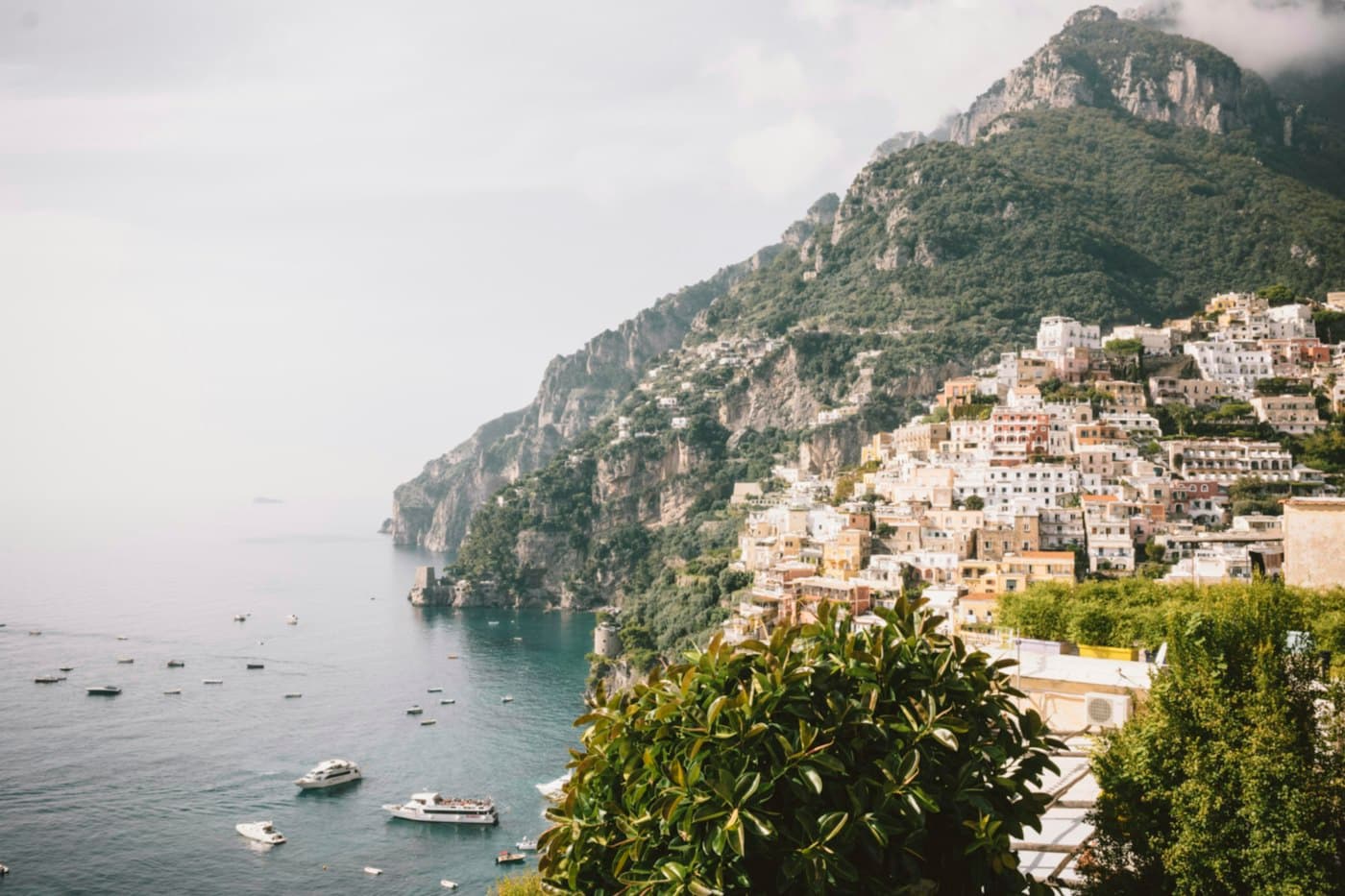 Le case di Positano sulla scogliera sopra una baia piena di barche, in una giornata velata