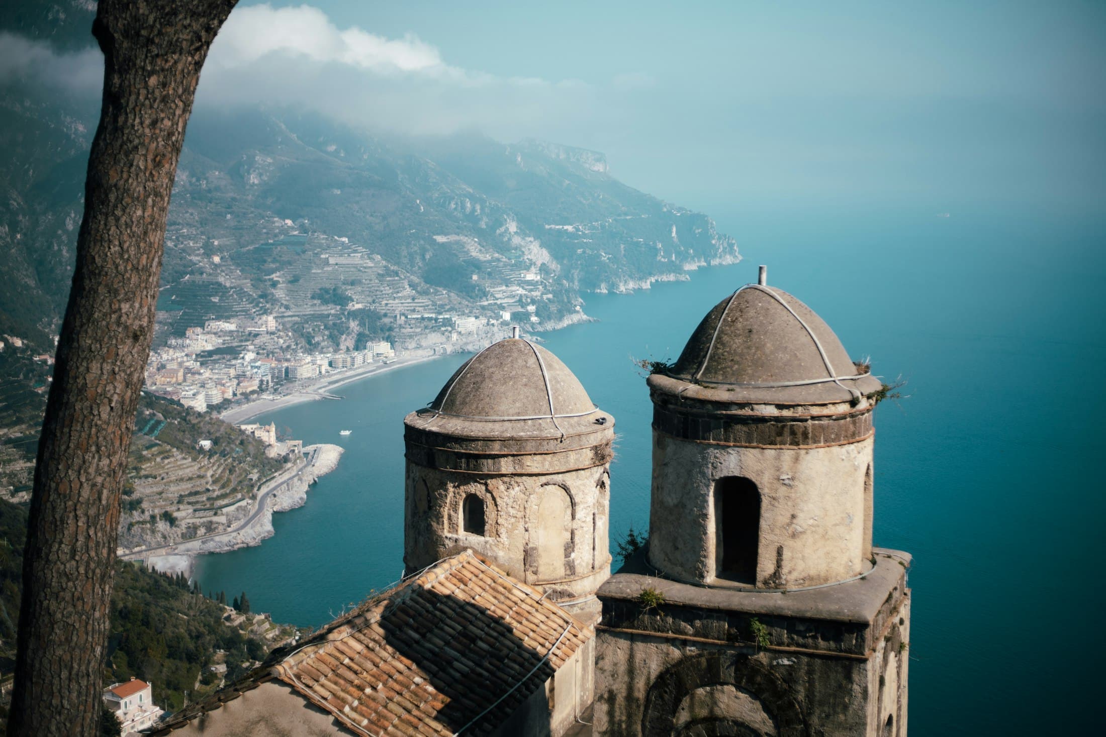Due antiche torri con la cupola a Ravello, alte sopra la Costiera Amalfitana, con un paese sulla baia molto più in basso