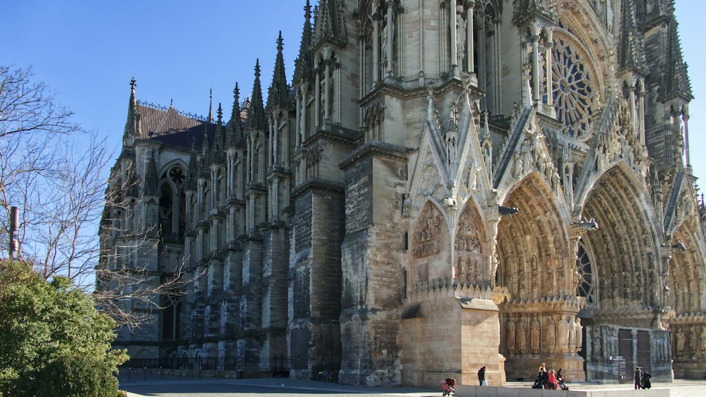 The carved portals of Reims Cathedral’s west front and the long buttressed flank of its nave in winter sun