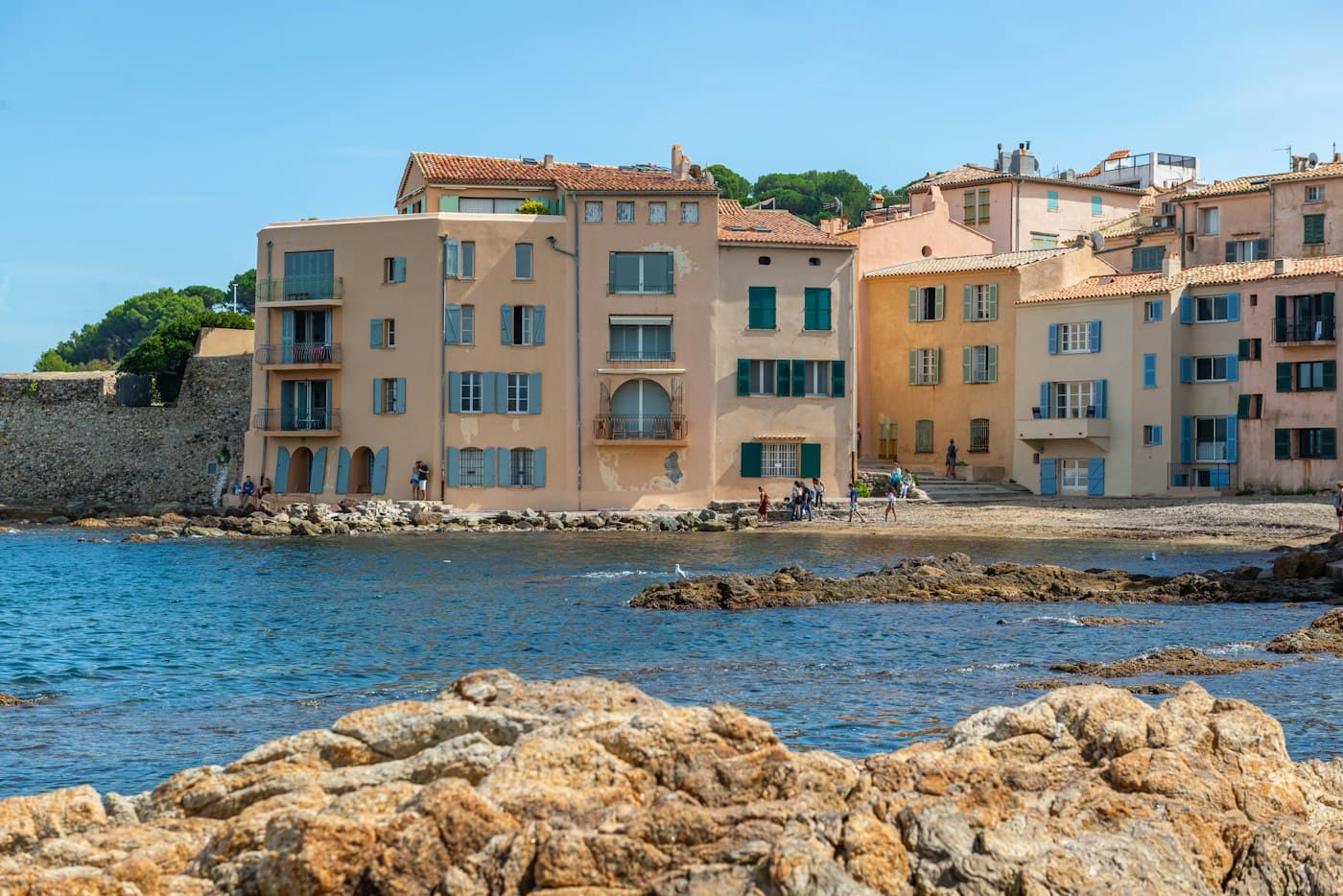 La Ponche in Saint-Tropez: pastel houses with blue and green shutters along the little beach, rocks and blue water in front
