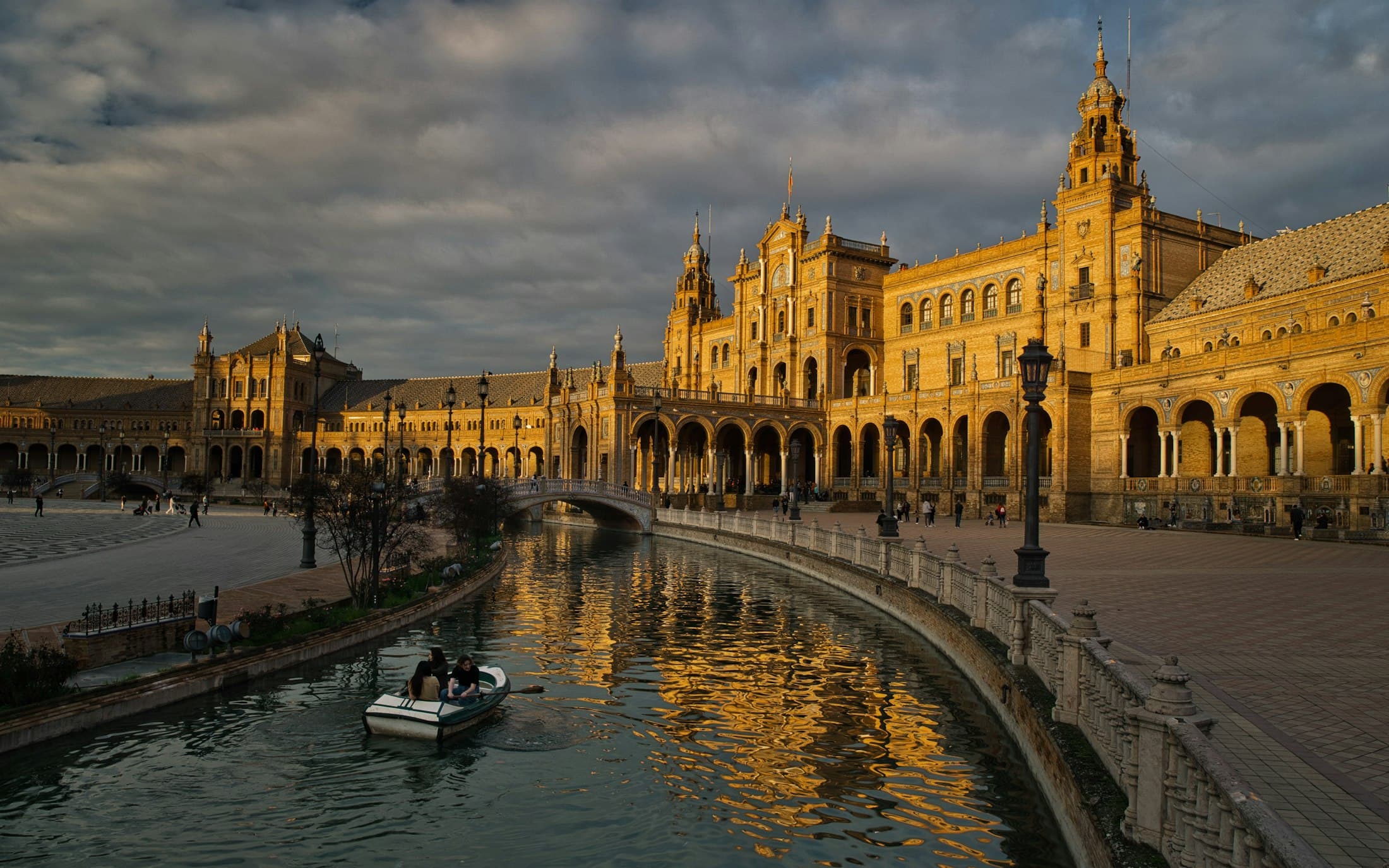 Plaza de España in Seville at sunset, a rowing boat on the canal below its brick arcades and towers