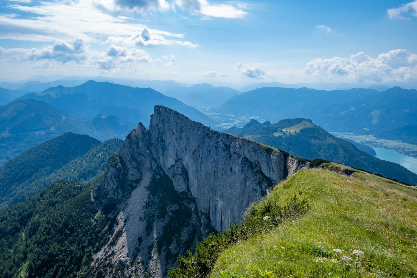The Schafberg’s sheer limestone wall below the summit ridge, a green crest in front and the Wolfgangsee shining in the valley on the right
