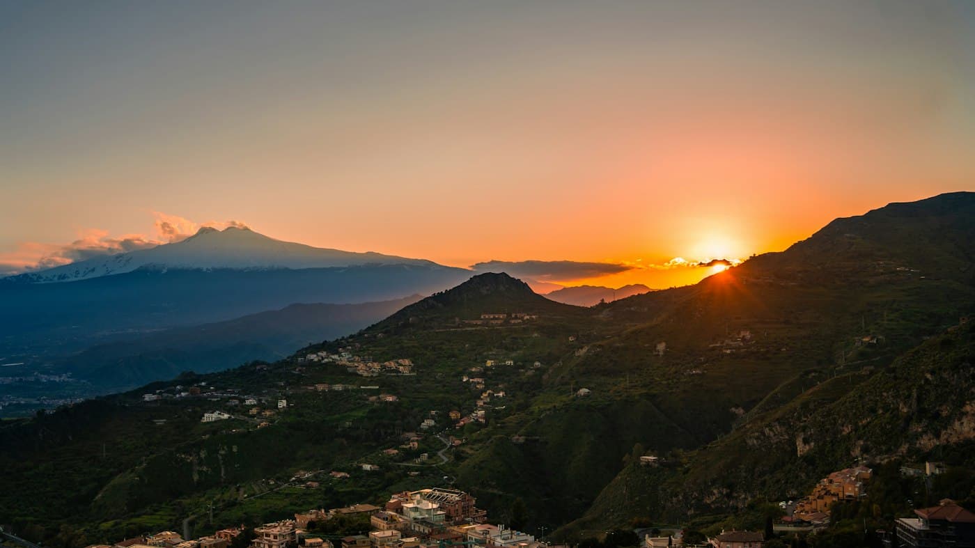 Sunset over the hills of Taormina, snow-capped Etna on the horizon