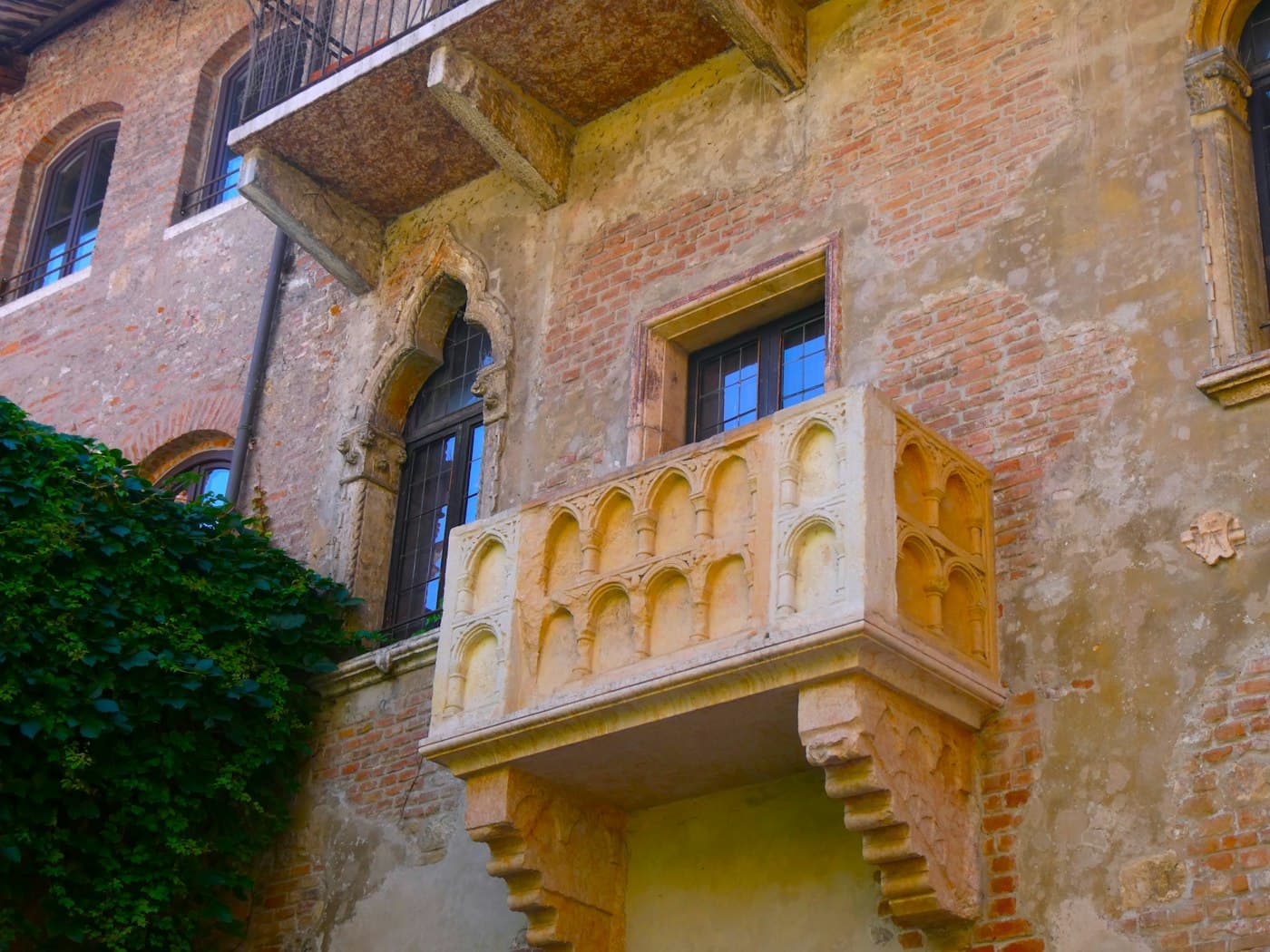 Il balcone di pietra scolpita della Casa di Giulietta a Verona sui vecchi muri di mattoni, con l’edera che sale accanto