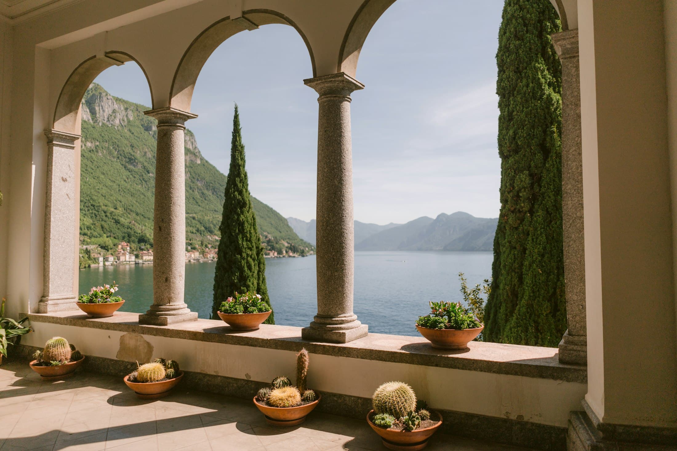 Uma galeria de arcos em pedra, com ciprestes, sobre o Lago de Como, em Varenna