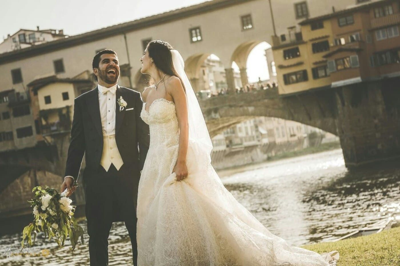 Noivos a rir junto ao Arno, em Florença, com a Ponte Vecchio atrás
