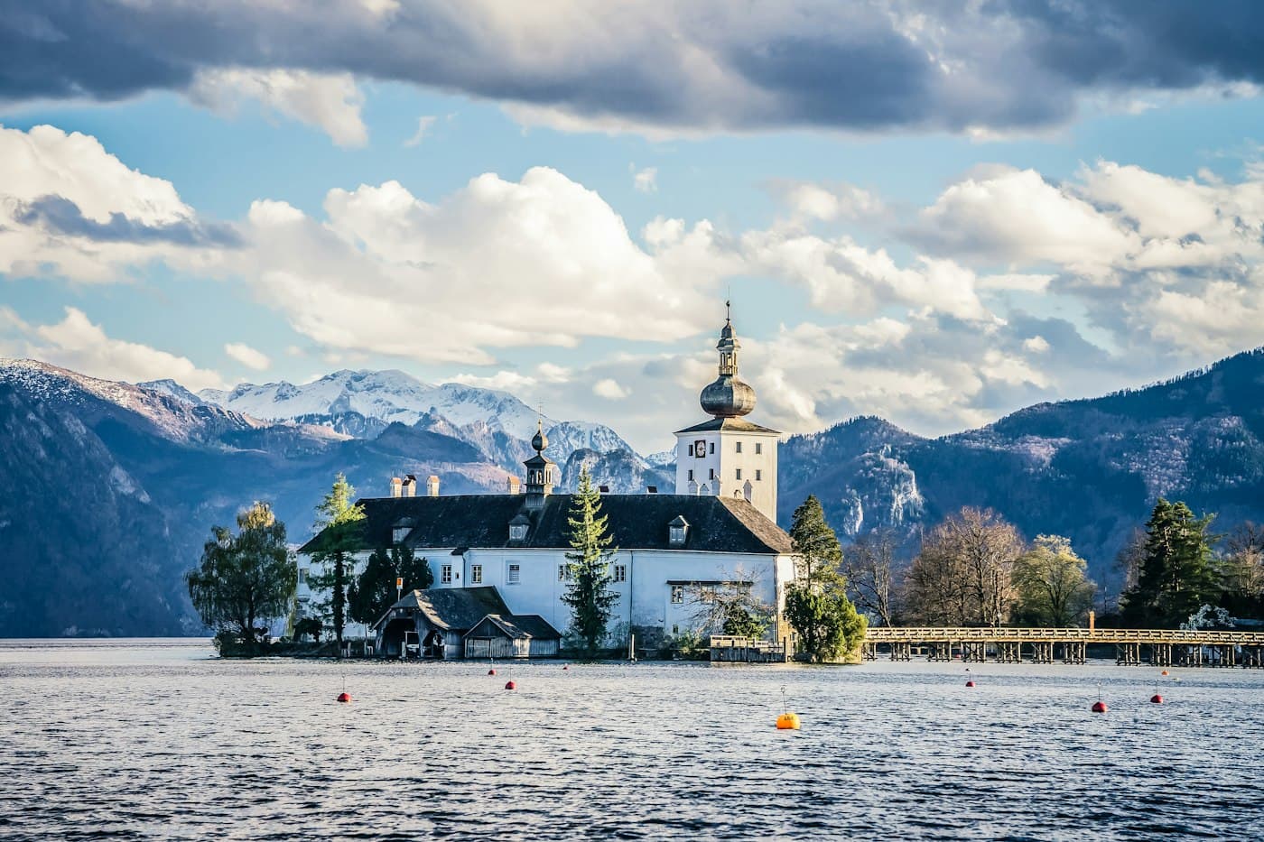 Lo Schloss Ort sul suo isolotto nel Traunsee, a Gmunden, con il ponte di legno verso la riva e la neve sulle montagne alle spalle