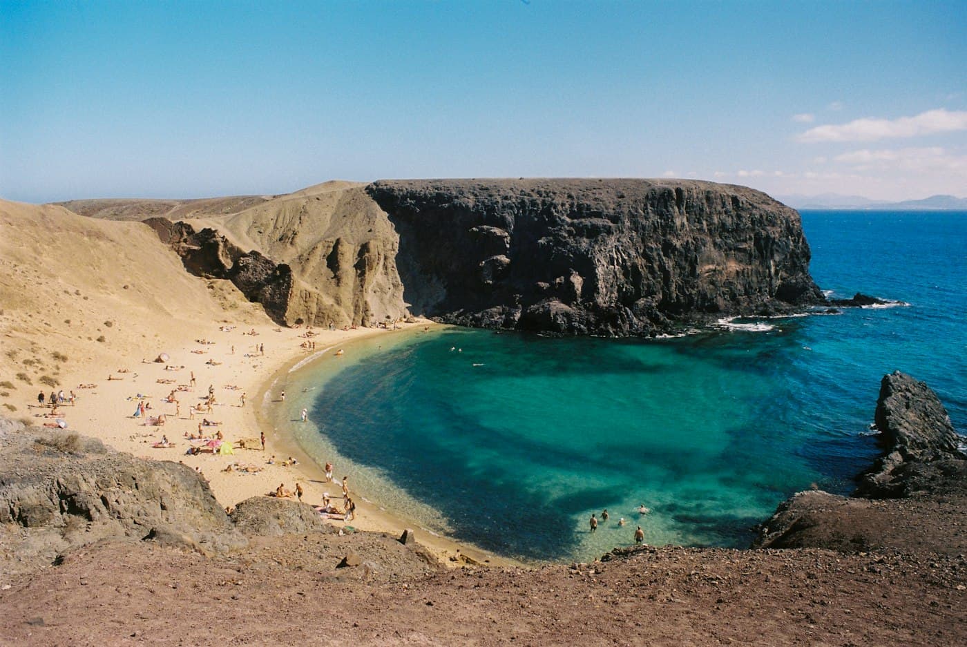 Uma enseada abrigada de água turquesa sob falésias escuras, em Lanzarote