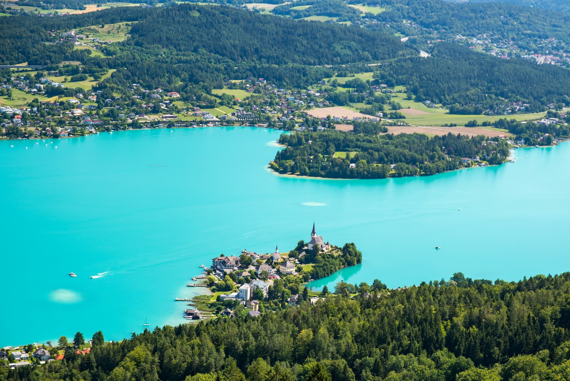 Maria Wörth mit seiner Kirche auf einer Halbinsel im türkisfarbenen Wörthersee, vom Pyramidenkogel aus gesehen
