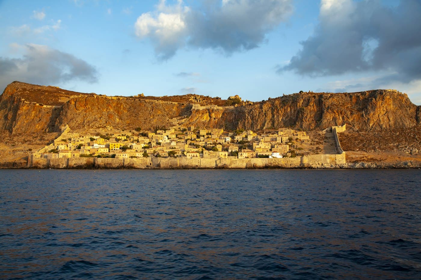 La ville basse fortifiée de Monemvasia au pied de son rocher, dans une lumière basse et dorée, vue de la mer
