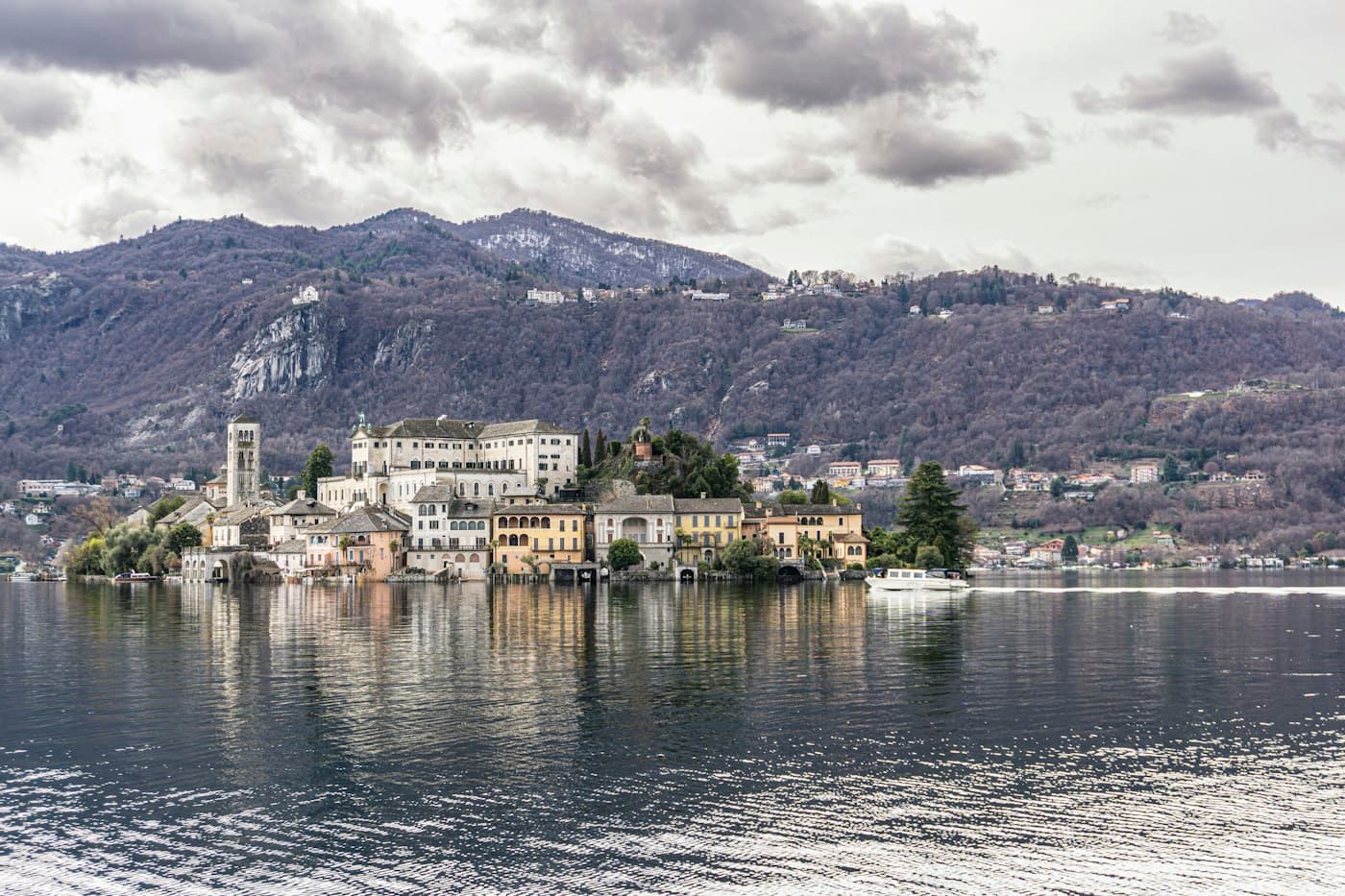 Die Insel San Giulio im Ortasee, Glockenturm und Häuser spiegeln sich im Wasser unter den Bergen