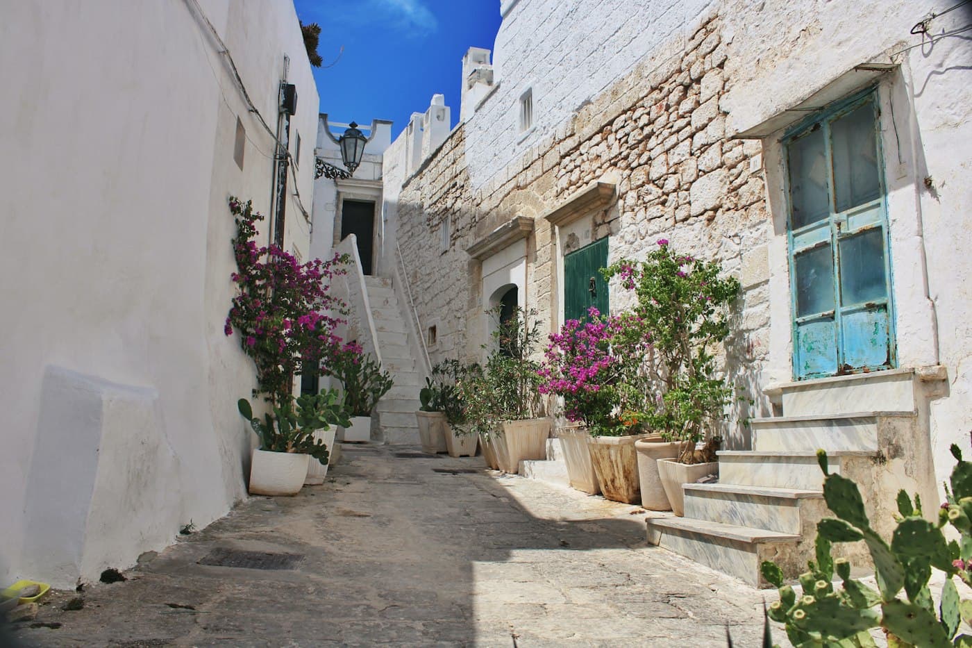 A whitewashed lane in Ostuni with bougainvillea and potted plants