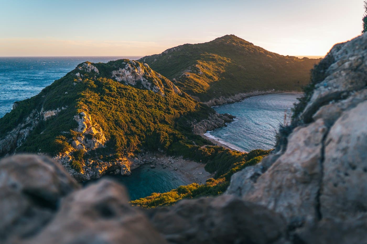 The twin bays of Porto Timoni on either side of a green headland, on Corfu’s north-west coast at golden hour