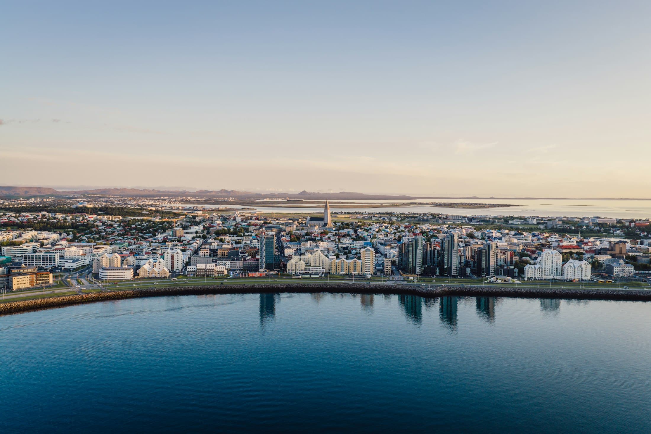 Reikiavik desde el aire con la luz de la tarde, la Hallgrímskirkja sobre los tejados y la bahía en calma delante