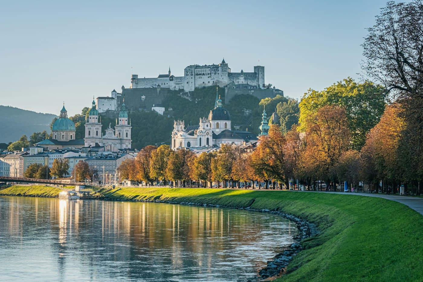 Die Salzach unter den Kuppeln und Türmen Salzburgs und der Festung auf ihrem Berg, das Ufer gesäumt von Herbstbäumen