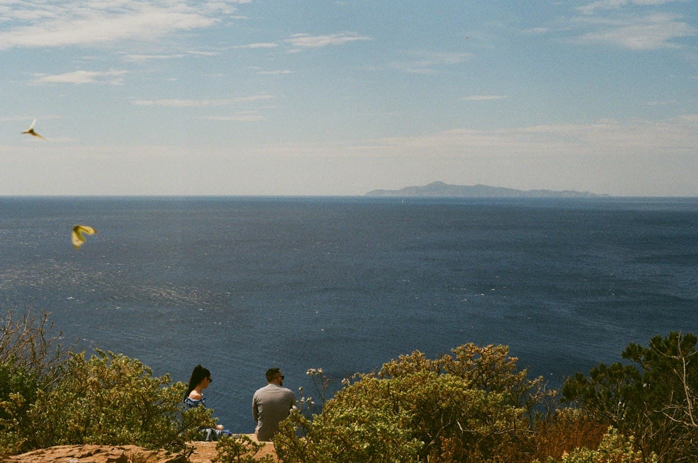 A couple sitting on the cliffs at Sounion, looking out to sea