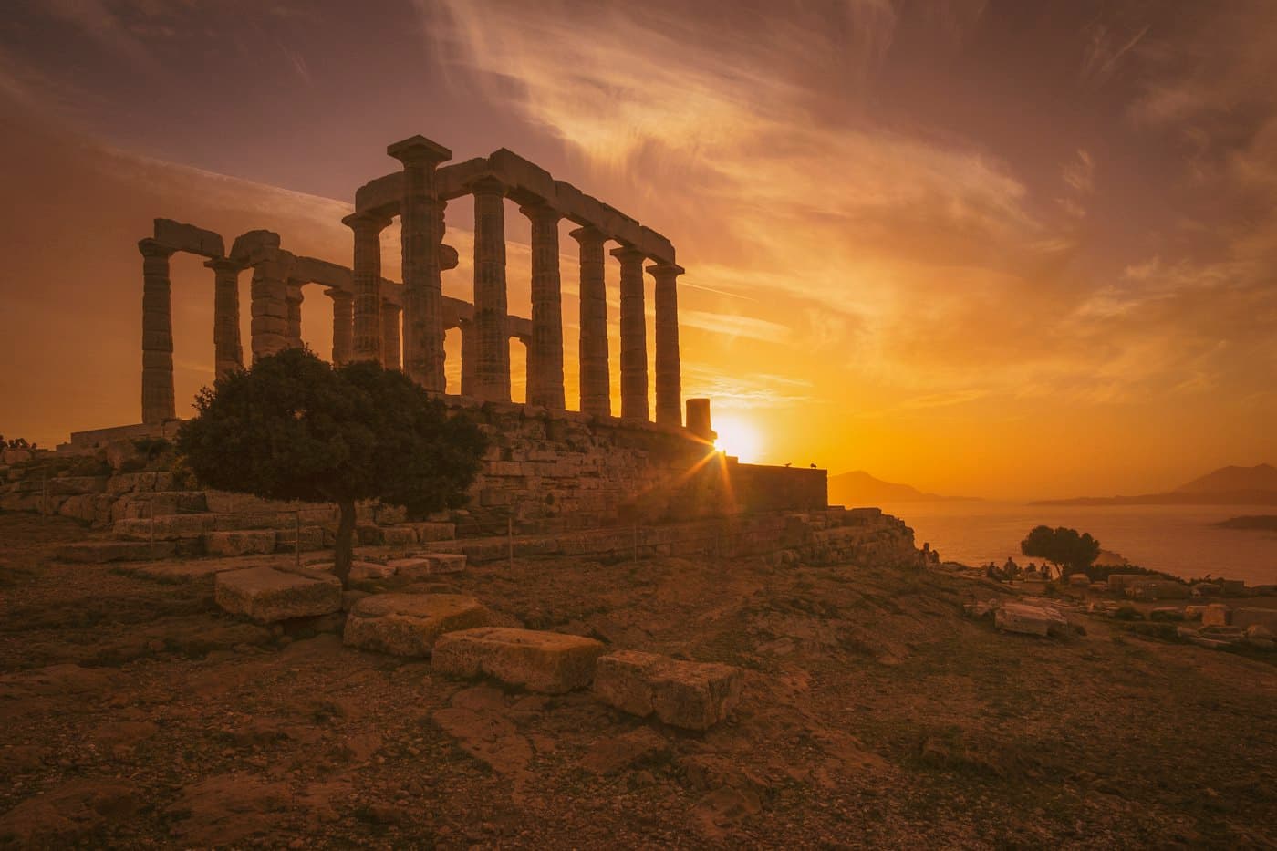Die Säulen des Poseidontempels am Kap Sounion vor der tief stehenden Sonne, dahinter das Meer
