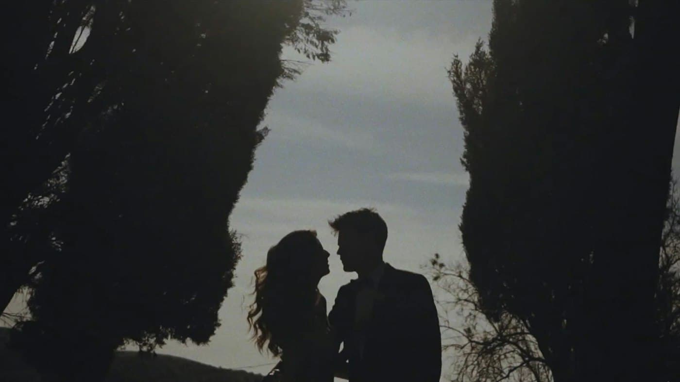 Um casal em silhueta entre dois ciprestes