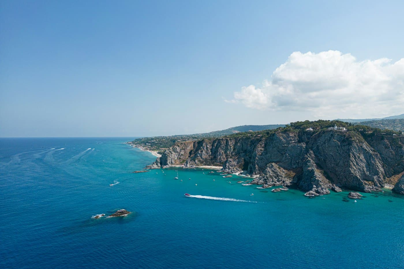 Die Klippen von Capo Vaticano aus der Luft, mit Booten in den türkisfarbenen Buchten darunter