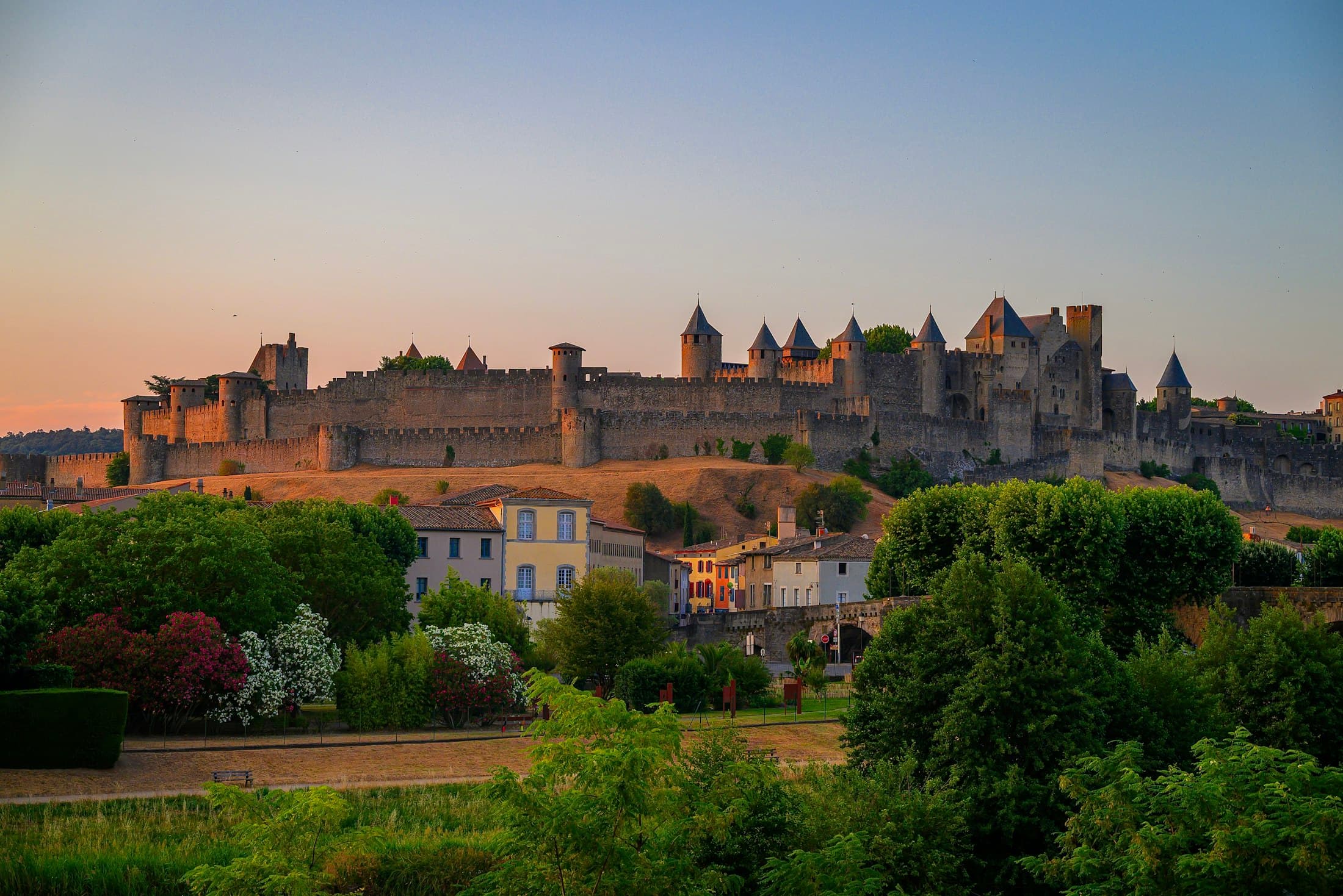 The towers and ramparts of Carcassonne’s Cité at sunrise, above the lower town and its gardens