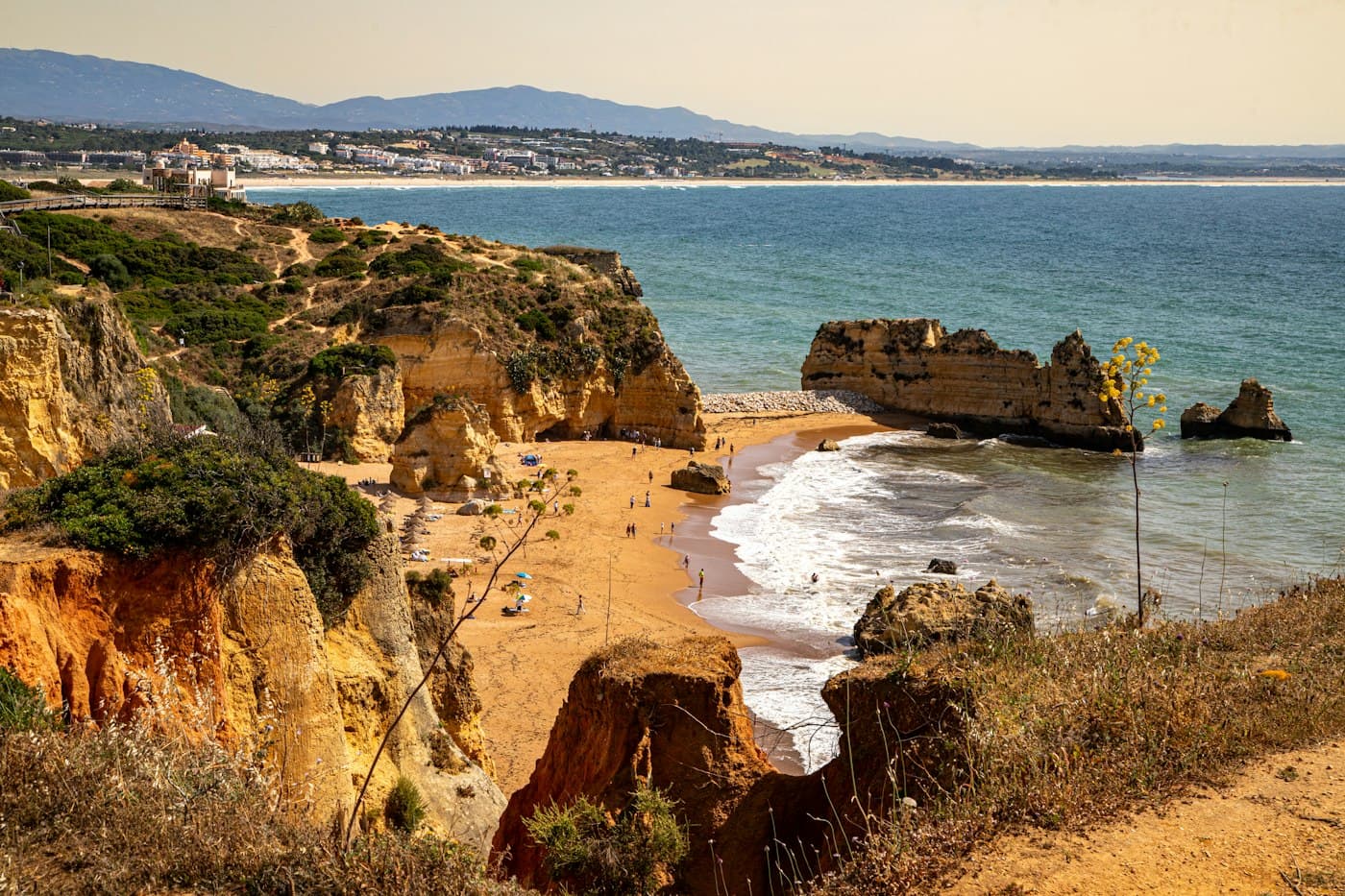 Golden cliffs above a sandy cove in Lagos, with the bay and the Algarve hills beyond