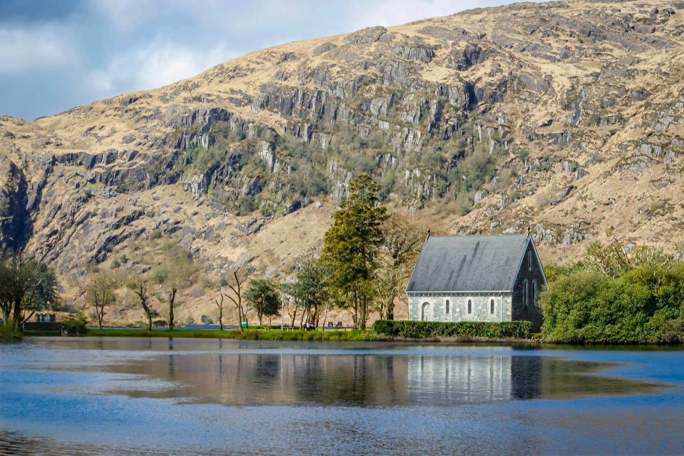 St Finbarr’s Oratory, a small stone chapel among trees on the lake at Gougane Barra, below a rocky mountainside