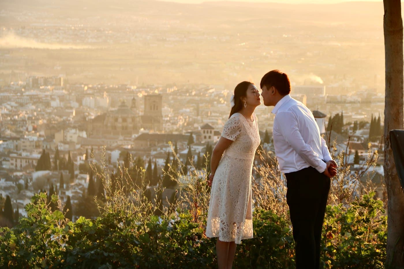 A couple kissing at a viewpoint above Granada at sunset