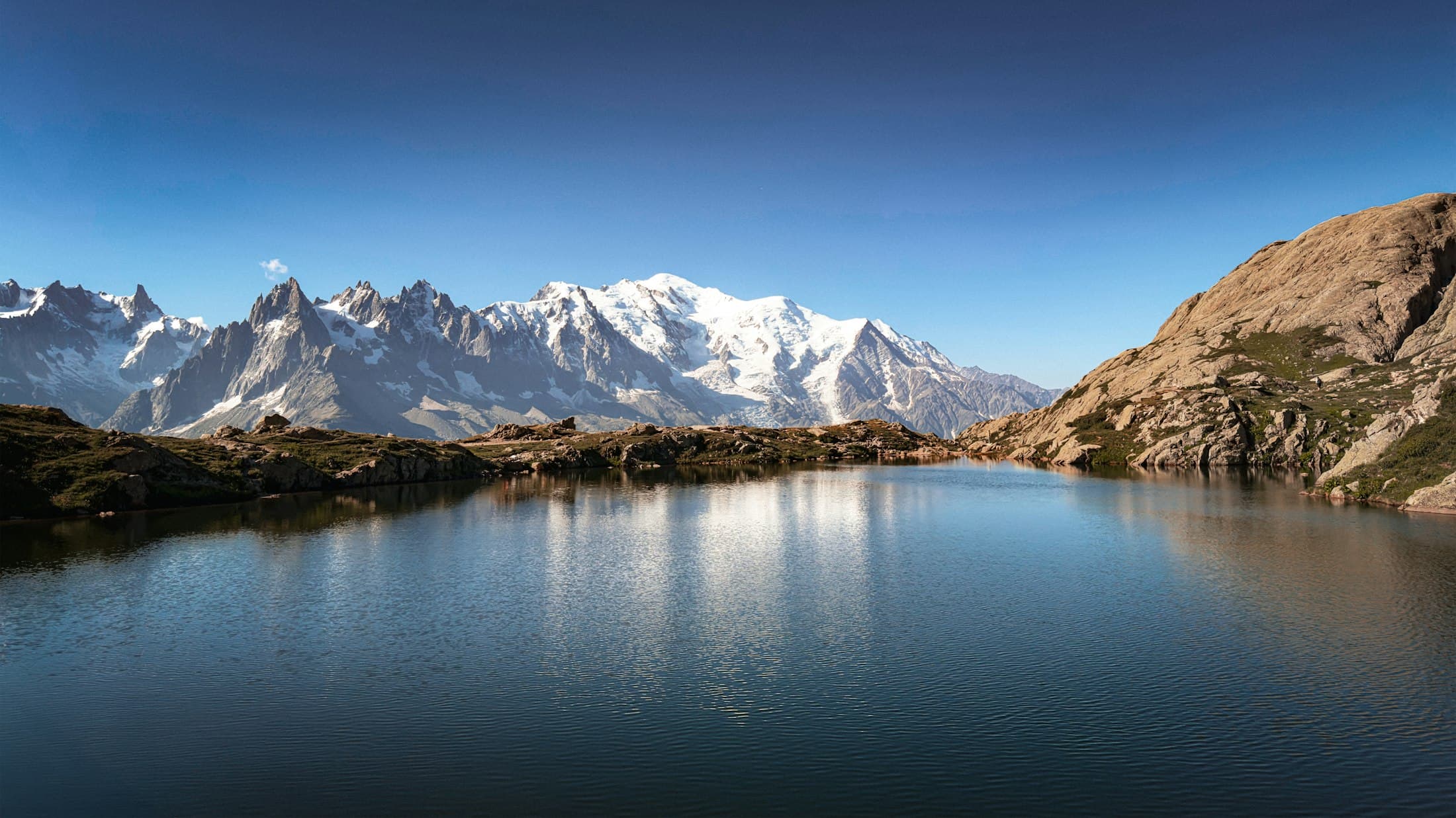 The snowy Mont Blanc massif above a still mountain lake near Chamonix