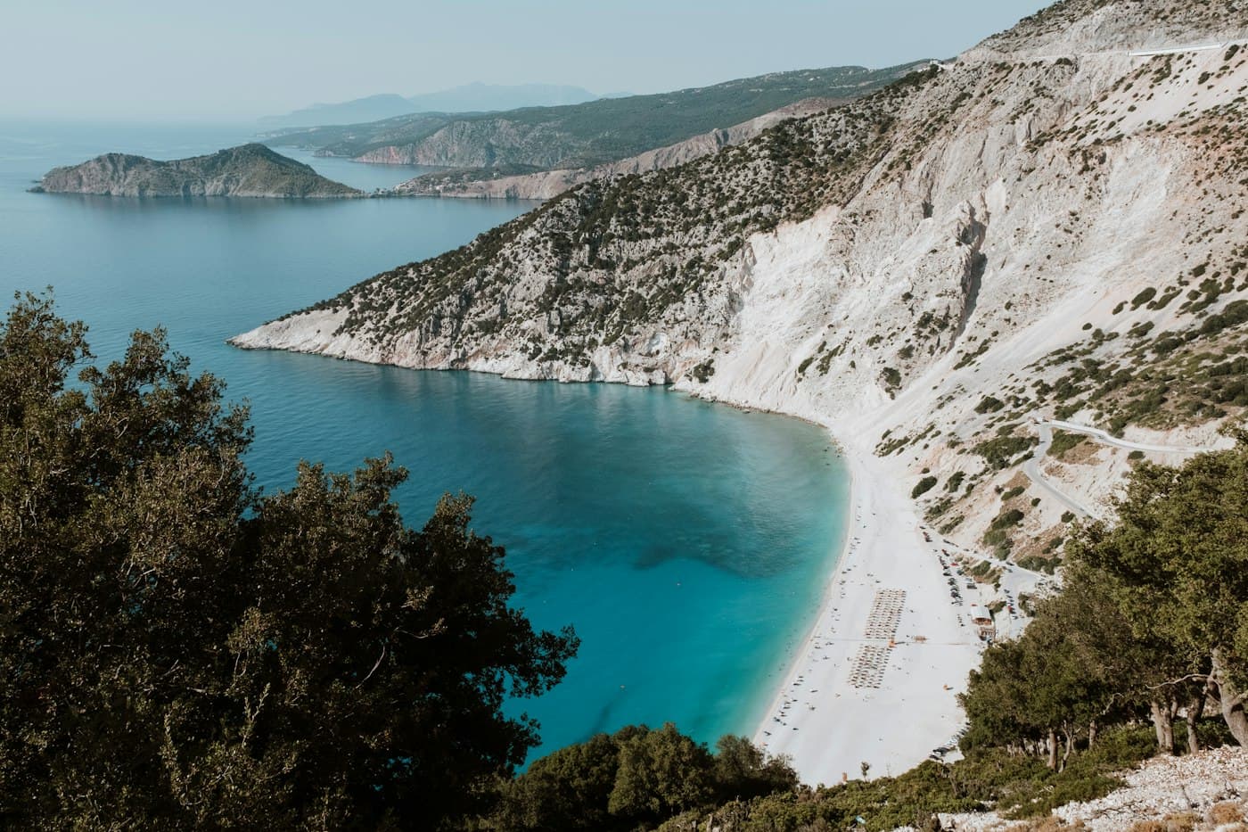 Der Strand von Myrtos auf Kefalonia: weiße Kiesel und türkisfarbenes Wasser unter hellen Klippen