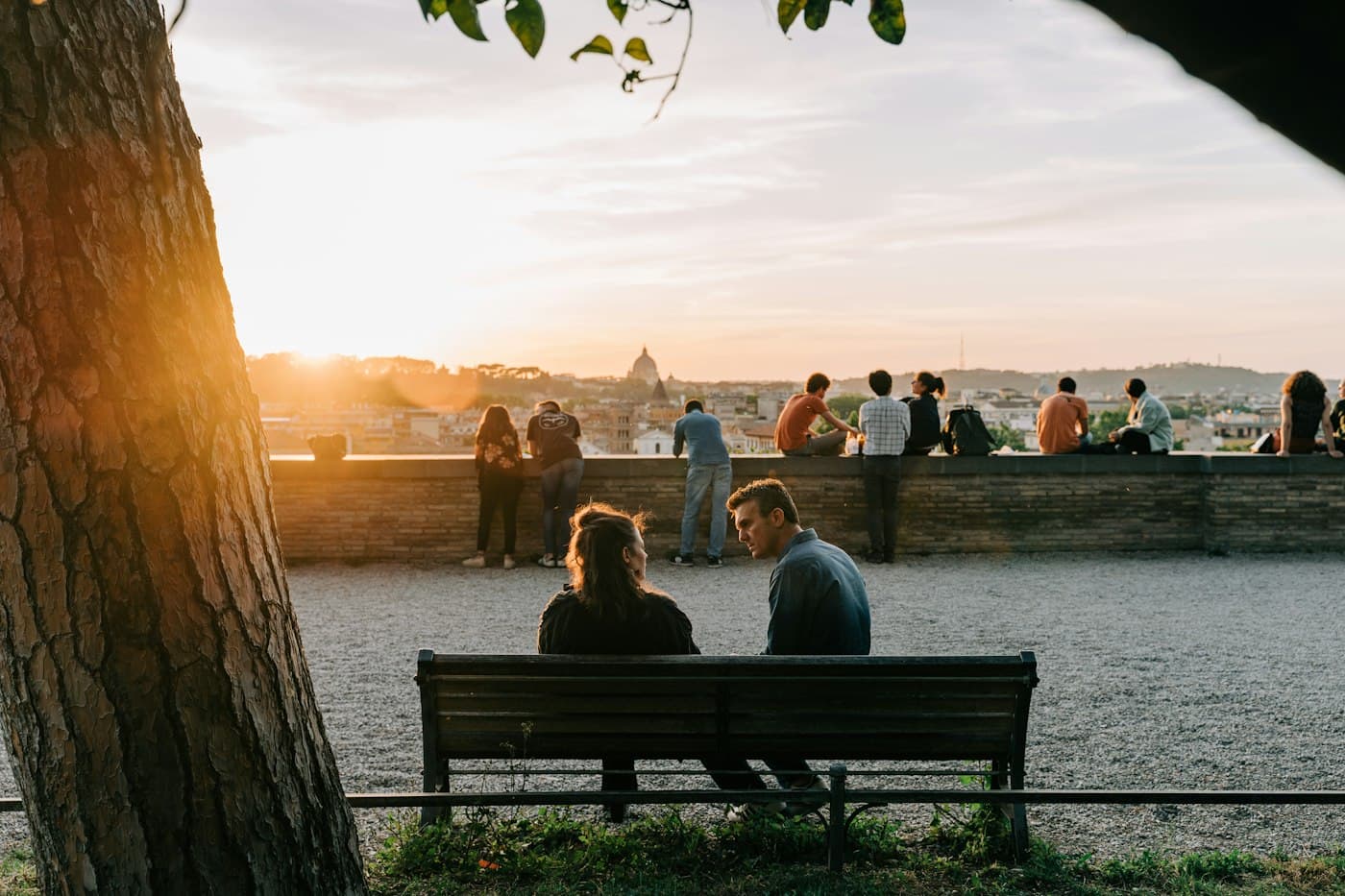 A couple on a bench at a viewpoint over Rome at sunset